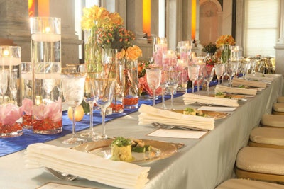 While most of the attendees dined at round tables, a long rectangular head table was reserved for the prize winner and his guests. On the tables were groupings of candle centerpieces with green cymbidium orchids and vases of varying heights containing bunches of roses, peonies, ranunculus, and orchids.