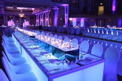Long, illuminated tables held rectangular vases wrapped in the Diffa logo and filled with floating votive candles.