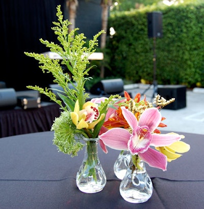 Circle of One topped highboys with colorful spring flowers in groups of three small vases.