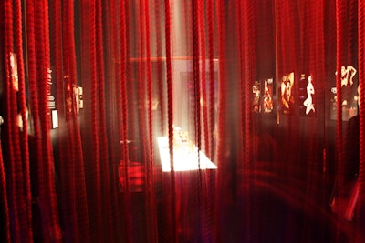 As a precursor to the theater, the second, cocoonlike room displayed an array of abstract motion graphics to represent key ideas behind Belle d'Opium. The space also referenced the perfume's packaging with a curtain of red rope and porthole-shaped frames for the video screens.