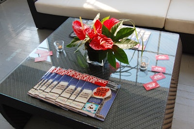 Copies of the redesigned magazine and vases filled with red anthurium topped tables throughout the cocktail space.
