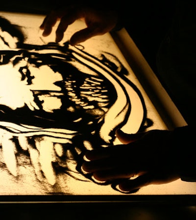 Richmond, Kentucky-based artist Joe Castillo draws in sand atop a light box.