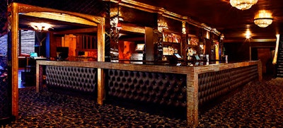 Crystal chandeliers hang over a quilted bar.