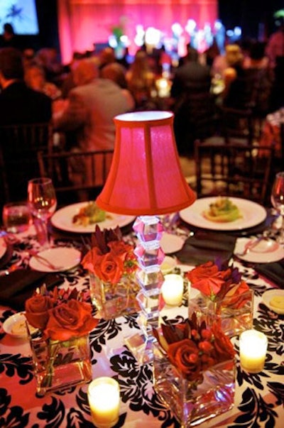 Blooming Design created centerpieces of mini red lamps surrounded by multiple small red floral arrangements in clear vases.
