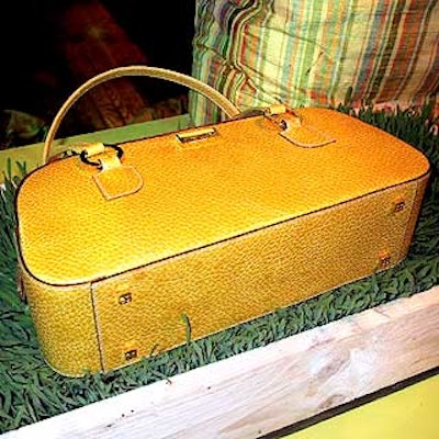 A Kate Spade purse in the green auction area was displayed in a pine wood box filled with grass.