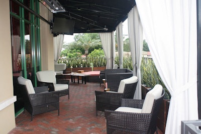 The large, draped terrace has a mix of lounge chairs, table seating, and a bar.