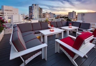 Seating at the Rooftop Lounge is comprised of white wooden chairs and sofas topped with plush gray and red cushions.