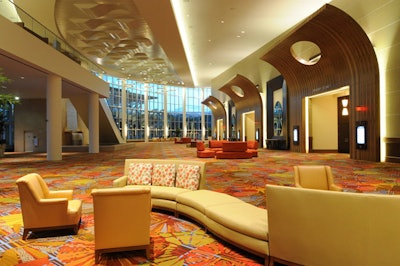 The prefunction space at the Peabody Orlando is decorated with bright carpet, dark wood, and contemporary furniture.