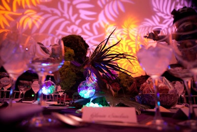 Centerpieces were composed of orchids, driftwood, LED lights, and suspended vegetation. The dinner lighting was intended to 'make guests feel as if they were dining under a luminescent canopy of trees,' said designer Jeffrey Foster.