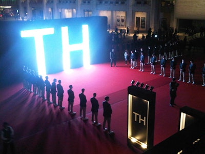 Upon exiting the tents after Hilfiger's Sunday night fashion show, guests were greeted by 50 staffers dressed in Tommy Hilfiger uniforms on a red carpet in front of the Metropolitan Opera House. The entrance was marked by a topiary bearing an illuminated 'TH,' a piece designed by Raúl Àvila, with graphic animations in the LED sign created by Rob Bishoff.