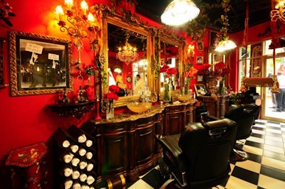The barbershop is decorated with vintage furnishings like gilded mirrors, antique chandeliers, and large black leather barber chairs.