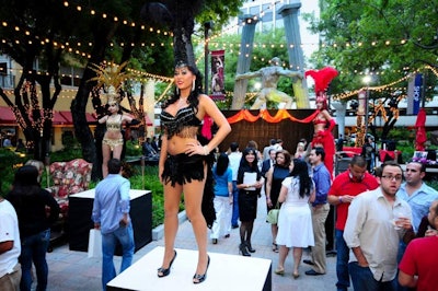 Costumed dancers with Las Vegas showgirl-style headdresses performed on raised pedestals throughout the event space.