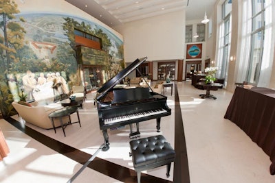 The living room is decorated with typical furnishings like sofas and club chairs, as well as a baby grand piano.