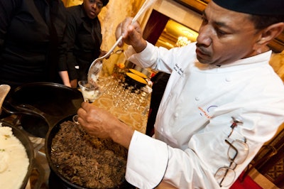 Gourmet Caterers chefs put the finishing touches on a beef dish served in a martini glass.