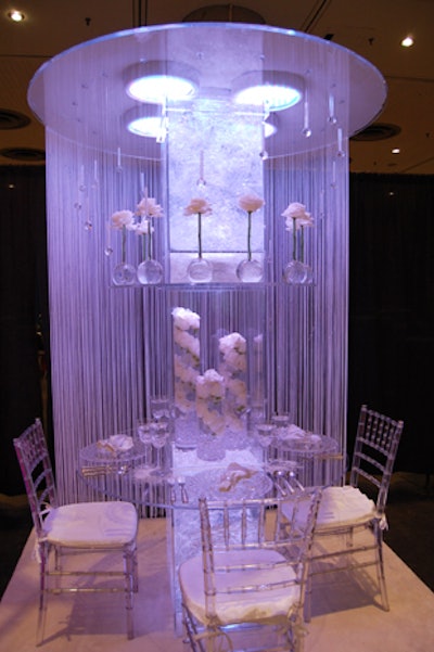 PBG Event Productions' 'White Roses on Ice' included white and clear rental items, as well as a tall center column that went through the table and displayed arrangements of white roses. Hanging crystals added to the frosty look.