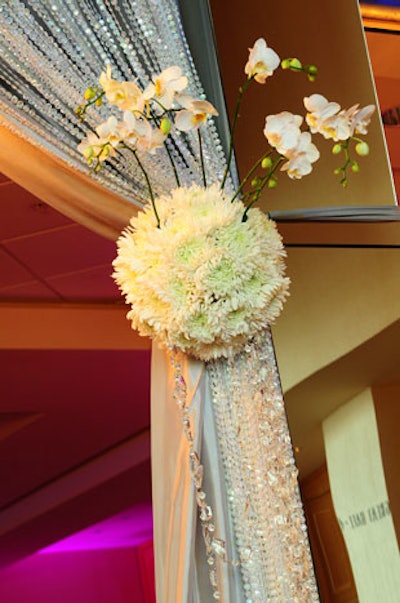 Floral tie-backs made out of white hydrangeas, mums, and orchids held back the ballroom's sheer silver draping.
