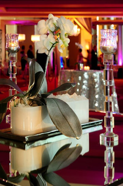 Mirrored tables added to the reflective feel of the cocktail reception area. The centerpieces each had a set of white orchids with leaves that were spray-painted silver.