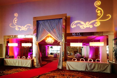 A single hanging chandelier and gobos drew attention to the doorway-shaped entrance that Donald Braun created using mirrored columns and silver draping. Guests referred to the frosted lettering above the tables to pick up their name tags.