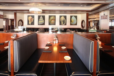 The decor inside Mitchell's Fish Market incorporates dark wood and nautical accents such as portholes, shells, and models of ships displayed in glass cases.