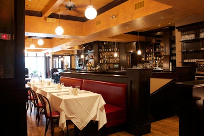 The bilevel space features dark mahogany, red leather booths, and large windows.
