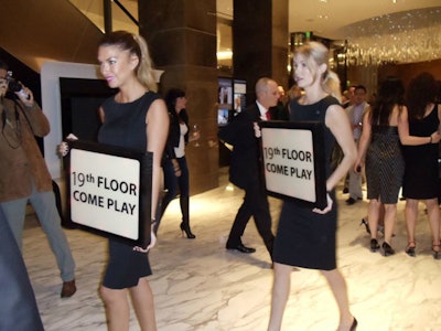 Models with signs helped usher guests up to the 19th floor for the party.