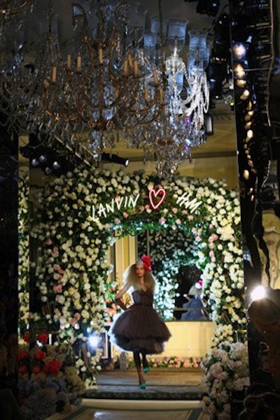 During the fashion show, models emerged from behind an illuminated runway backdrop, an arch of fresh roses and peonies made by Raúl Àvila.