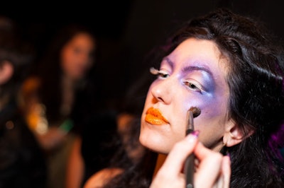 Makeup artist Michelle Clark and her team put the finishing touches—purple and blue eyeshadow and orange-tinted lips—on models backstage.