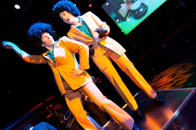 The two greeters, dressed in period-perfect bell-bottoms and Afro wigs, danced on platforms during the preshow reception.