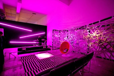The 'edgy' boutique room featured a 30-foot-long mirrored Mylar weblike backdrop, and a black wall with long fluorescent tube lights that emitted a purple glow. Black leather furnishings anchored the space and matched a black and white graphic rug and a red egg chair.