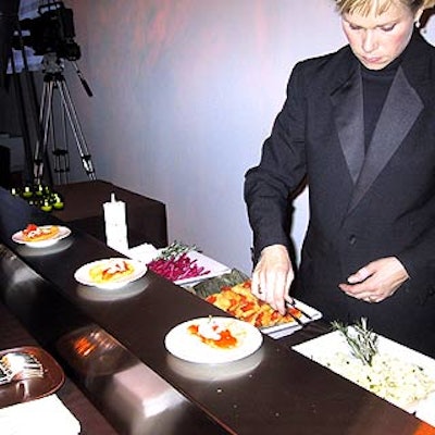 Servers from Tentation prepared food behind stations made of long, rectangular blocks of stainless steel.