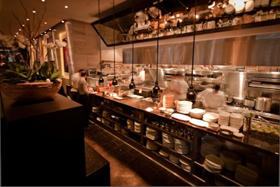 An oversize mirror hangs from the ceiling above the open kitchen, offering views of the chefs at work.