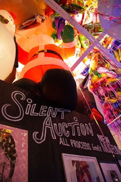 Chandelier Creative place custom-built black walls over the bookshelf-lined walls of its library, allowing art to be displayed for the silent auction. Two massive inflatable Christmas balloons—a snowman and Santa Claus—were positioned above the partition.