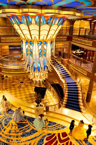 The atrium lobby is anchored by a grand staircase below and a commanding Art Deco chandelier.