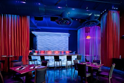 The room is accented with red and blue floor-to-ceiling drapes, some of which wrap around the four circular booths.