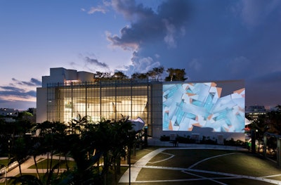 The glass wall on the left of the facade provides a view into the atrium, while the large projection wall on the right can be used for outdoor presentations.