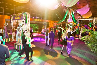 The cocktail hour included over-the-top Mardi Gras decor in the form of 10-foot masquerade masks, draping, costumed women on stilts, body-painted performers, and green, purple, and yellow lighting.