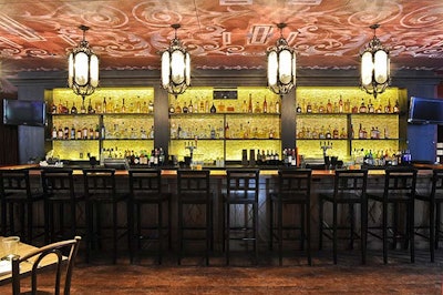 A bar with overhead lanterns and cinnamon-hued painted ceilings seats 15.