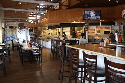 The nautical-theme restaurant has seating at tables and a bar, all with a view of the open kitchen.