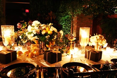 The lush greenery of the dinner space extended to the tabletop, where vines, arrangements of white and green flowers, and branches of Meyer lemons surrounded tall candelabra, Italian terra-cotta compotes, and gold-rimmed black chargers.