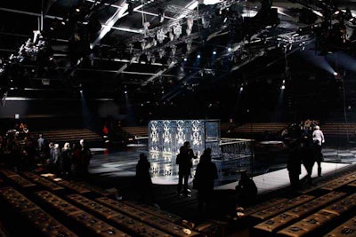 Inside Louis Vuitton's blacked-out venue, a glossy square-shaped runway was decorated with a checkerboard pattern and matched by black faux leather cushioned seats for guests. Adding to the dark atmosphere was the use of a single spotlight on each model as she walked, leaving the rest of the space unlit.