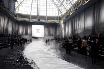 In stark contrast to the igloo-like setting it created last March, Chanel's show on March 8 was made to look like the inside of a volcano. Held once again at the Grand Palais, it included scenery such as smoldering rocks, synthetic volcanic ash, dry ice to emulate steam, and a 525-foot-long curved wooden catwalk.