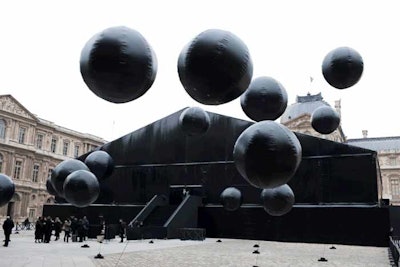 Huge black PVC balloons bobbed overhead as guests arrived at Louis Vuitton show on March 9. Constructed in a courtyard at the Louvre, a dramatic, all-black tent coupled with the dozens of French chambermaids that served as greeters set the tone for the show's fetishist motif.