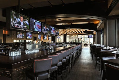 The venue's design is replete with hardwood floors, dark brown leather seating, and floor-to-ceiling windows.