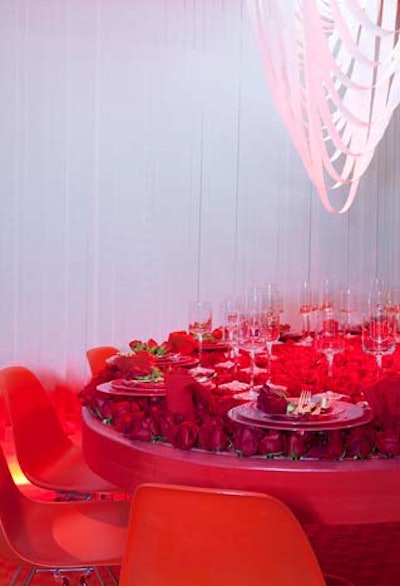 Guests at David Rockwell's table dined from plates set on a bed of fresh red roses. Inspired by the AIDS ribbon, Rockwell used plain ribbon to create an interwoven hanging display in lieu of a chandelier.