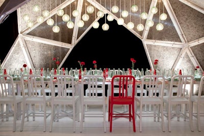 Stefan Beckman created a sleek, on-brand table for sponsor Coca-Cola using a variety of recycled items, including the overhead lights and dining chairs (which were made from plastic bottles). Clear glass vessels, including some empty Coke bottles, created a runner down the center of the table.