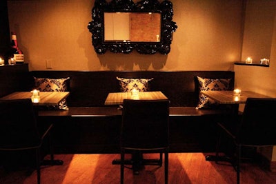 Two-top tables and wooden banquettes provide seating at the rear of the lounge.
