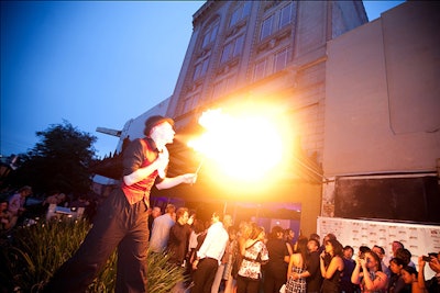 While guests waited to enter the party, an entertainer on stilts performed tricks with fire.