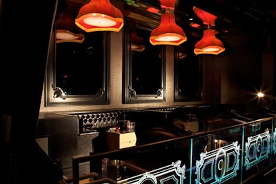 Red lamps hang over tufted black banquettes.