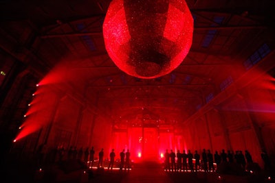 Cued by music, the laser-wielding male staffers motioned to the opening of a long red wall, behind which stood a 15,000-square-foot party space. An oversize red disco ball, which measured 15 feet in diameter, hovered above the Ming temple, which was surrounded by thousands of candles and flickering red LED lights.