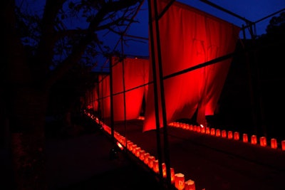 Diane von Furstenberg's voice, projected through speakers, welcomed guests to the gala, the entrance of which was marked by a 500-foot-long runway of red fabric attached to bamboo gates. Thousands of candles, each placed inside red paper bags perforated with the designer's initials, lined the path.